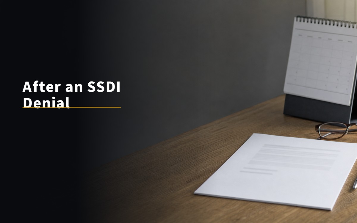 After an SSDI Denial. Denial notice and calendar on a clean desk in soft daylight.
